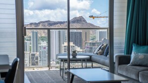 A modern living room with a large window, a sofa, a coffee table, and a view of a mountain and cityscape.