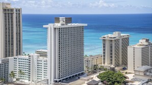 A high-rise hotel with multiple floors, a central courtyard, and a view of the ocean.