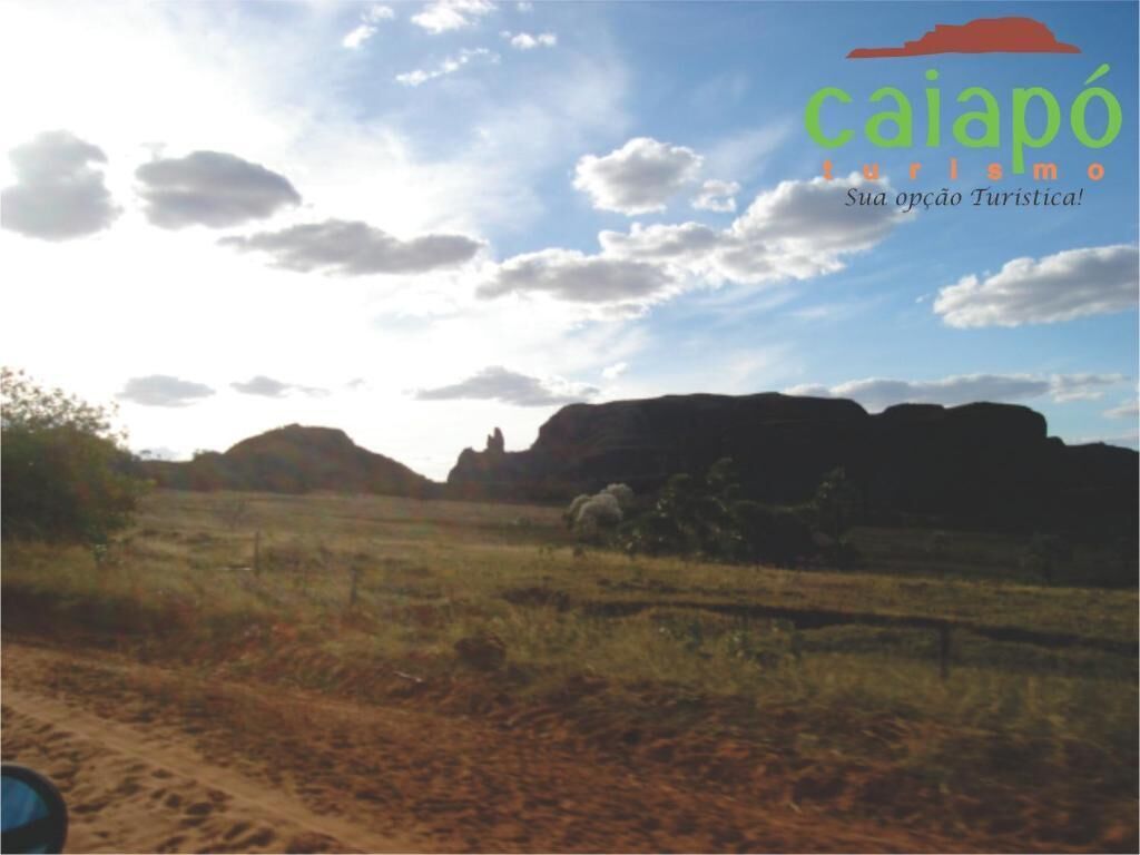 A landscape with a dirt path and rocky formations under a partly cloudy sky.