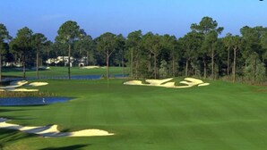 Un parcours de golf avec des bunkers de sable, des obstacles d’eau et un ciel dégagé.