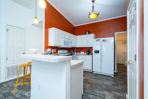 Kitchen area with central island, microwave, and pendant lights.