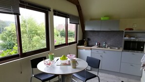 A kitchen with a dining area, large windows, and a view of greenery. - Spacious accommodation surrounded by greenery (Mouliherne)