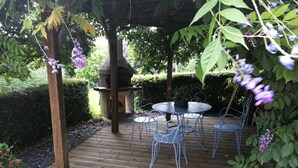 A wooden deck with a pergola, a round table, and four chairs. - Spacious accommodation surrounded by greenery (Mouliherne)