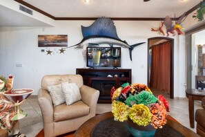 A living room with a beige sofa, a large decorative fish sculpture, and a colorful flower arrangement.