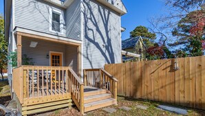 A two-story house with a wooden porch and a wooden fence.