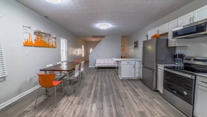 A modern kitchen with white cabinets, stainless steel appliances, and a dining area with a wooden table and chairs.
