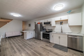Una cocina moderna con armarios blancos, electrodomésticos de acero inoxidable y piso de madera.