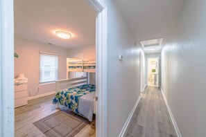 Un dormitorio con literas, una mesita de noche y una ventana con persianas.