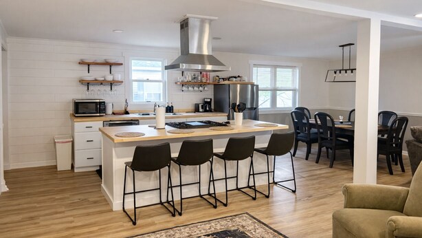Una cucina moderna con isola centrale, sgabelli da bar e zona pranzo con sedie.