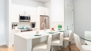 Una cocina moderna con armarios blancos, electrodomésticos de acero inoxidable y una isla central con asientos.
