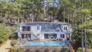 Ett tvåvåningshus med en swimmingpool, en täckt veranda och utsikt över den omgivande skogen.