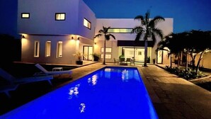 Ein modernes Haus mit Schwimmbad im Abenddämmerung.