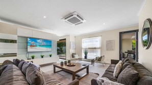A modern living room with a flat-screen TV, a coffee table, and a sofa. - Villa Haven: 6BR w/ Private Pool Near Palm Beach! (Noord)