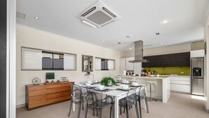 A modern kitchen with a dining area, featuring a central island, a built-in oven, and a stainless steel refrigerator. - Villa Haven: 6BR w/ Private Pool Near Palm Beach! (Noord)