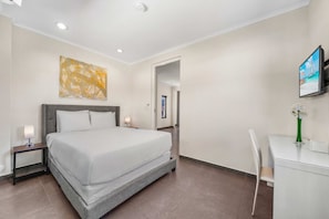 A hotel room with a bed, bedside tables, a desk, a chair, a painting, and a television.