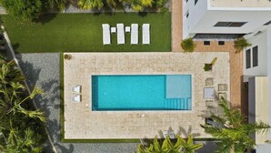 An aerial view of a swimming pool with sun loungers and a small deck area. - Villa Haven: 6BR w/ Private Pool Near Palm Beach! (Noord)
