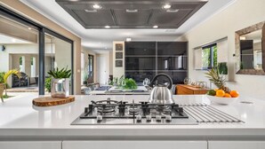 A modern kitchen with a gas stove, stainless steel appliances, and a large window. - Villa Haven: 6BR w/ Private Pool Near Palm Beach! (Noord)