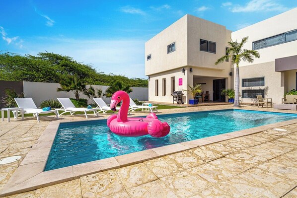 A swimming pool with lounge chairs and a pink flamingo float.