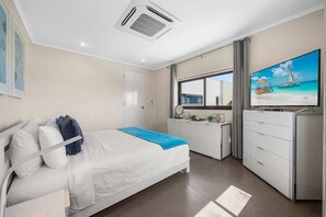 Ein Hotelzimmer mit Bett, Schreibtisch, Fernseher und Fenster mit Blick auf den Strand.