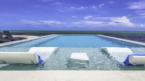 Una piscina con sillas de descanso y vista al océano.