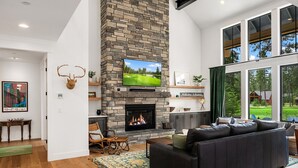 A spacious living room with a stone fireplace, a large flat-screen TV, and a comfortable seating area.