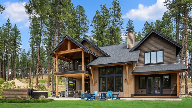 A two-story log cabin with a balcony and a covered patio area.