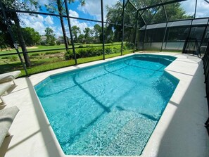 A rectangular pool with clear blue water, surrounded by a white deck and a metal fence.