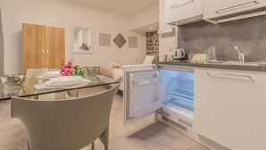 Eine moderne Küche mit Einbaukühlschrank, einem Essbereich mit Glastisch und einem Holzkasten.