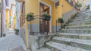 Eine schmale Gasse mit Steinstufen, die zu einem gelben Gebäude mit einer Holztür und Metallgeländern führt.