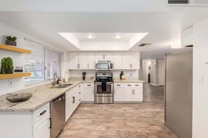 A modern kitchen with white cabinets, stainless steel appliances, and a skylight. - Obispo Modern Oasis with Heated Pool and BBQ (Mesa)