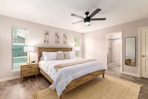 A bedroom with a bed, bedside tables, a ceiling fan, a window with blinds, and a door. - Obispo Modern Oasis with Heated Pool and BBQ (Mesa)