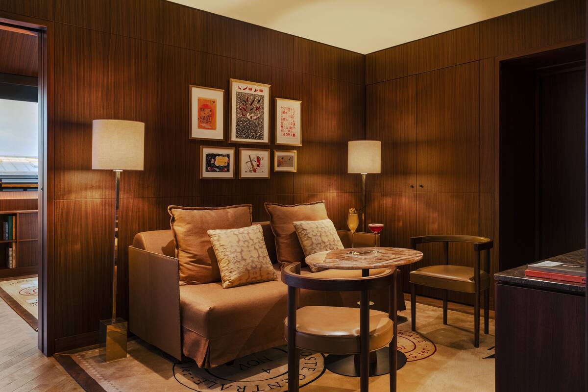 A cozy room with a sofa, two chairs, a small table, and wall-mounted lamps.