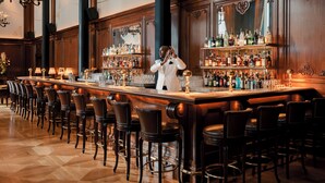 A bar with a long counter, multiple stools, and a variety of bottles and glasses. - Hôtel Madame Rêve (Paris)
