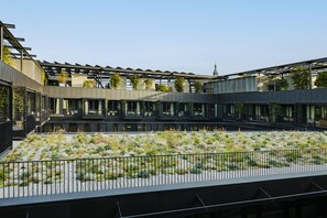 A modern building with a covered outdoor area and a landscaped garden. - Hôtel Madame Rêve (Paris)