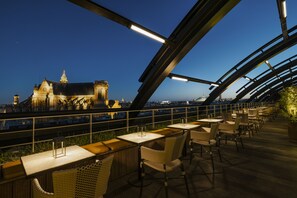 An outdoor dining area with tables and chairs, overlooking a historic building with a clock tower. - Hôtel Madame Rêve (Paris)