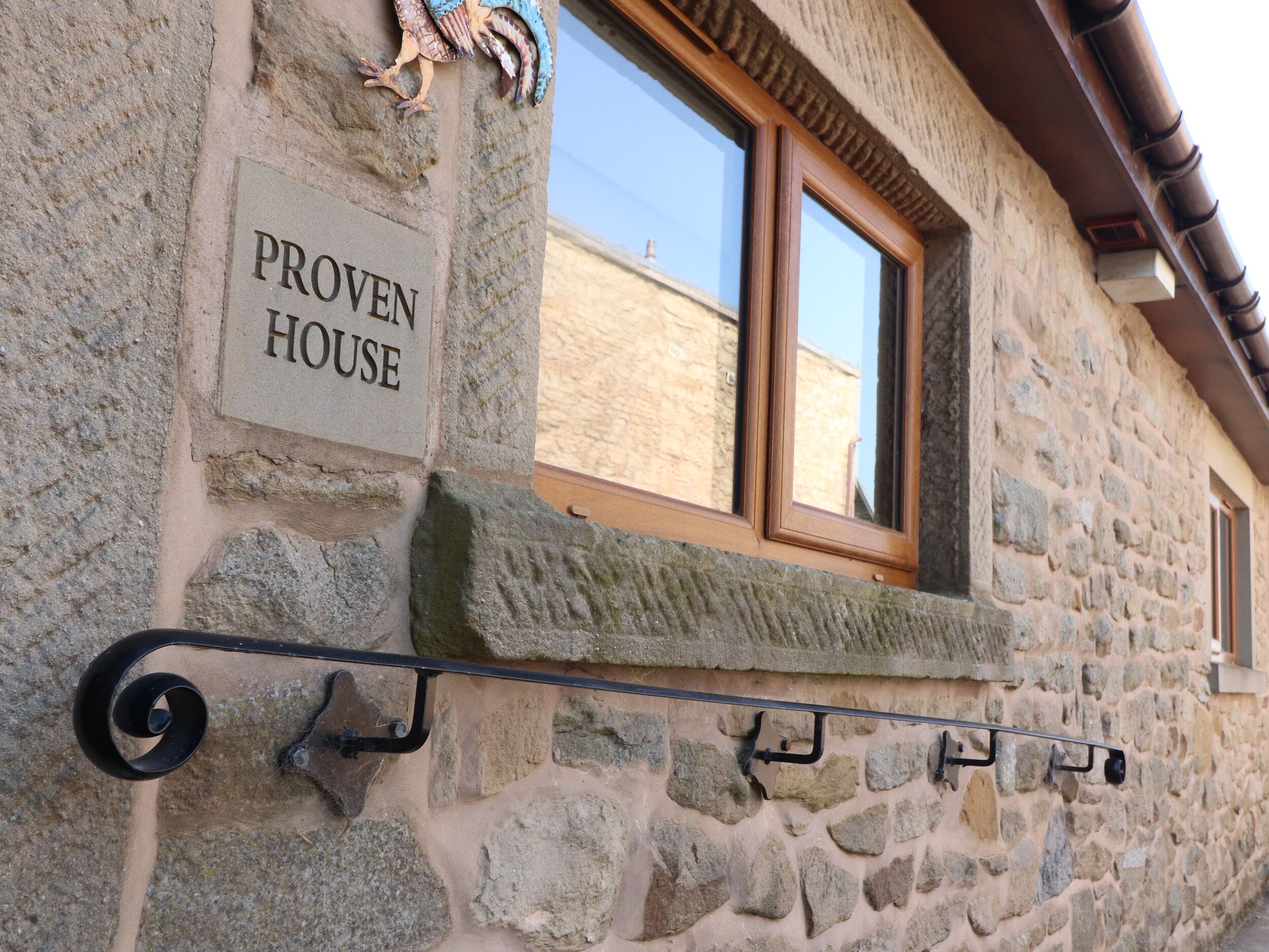 A stone building with a sign reading "PROVEN HOUSE" and a window with a wooden frame.