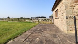 A stone building with a paved pathway leading to a wooden fence. - The Proven House (Preston)