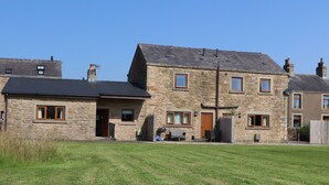 A stone house with a sloped roof, multiple windows, and a front door. - The Proven House (Preston)