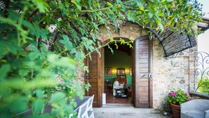 A rustic stone building with wooden doors and a brick archway. - Le Rose di Montagnana (San Gimignano)