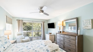 A bedroom with a bed, a chair, a dresser, a television, and a balcony. - Lagoon Villa 19 - Lagoon Lifestyle! Center Resort! (Isle of Palms)