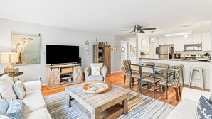 A modern living room with a TV, sofa, coffee table, and dining area. - Lagoon Villa 19 - Lagoon Lifestyle! Center Resort! (Isle of Palms)