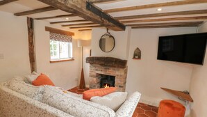 Una sala de estar con sofá, chimenea, televisor y ventana con vistas a zonas verdes.