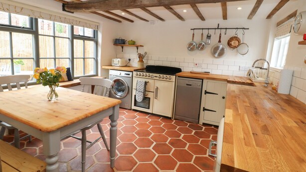 Una cocina con una mesa de madera, lavadora, horno y lavavajillas.