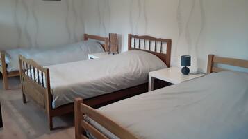 Ein Zimmer mit zwei Holzbetten, einem Nachttisch mit Lampe und einem gerahmten Bild an der Wand.