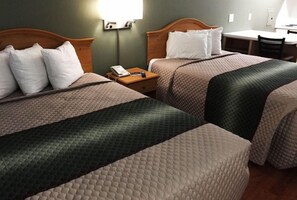 Habitación de hotel con dos camas, un escritorio y una silla.