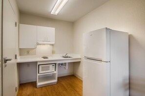 A compact kitchen with white cabinetry, a built-in microwave, and a refrigerator.