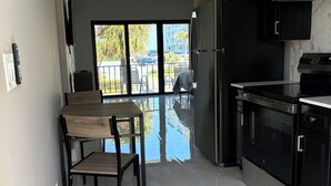 A modern kitchen with a dining area, large windows, and a view of the outdoors. - Oceans 735 (Deerfield Beach)