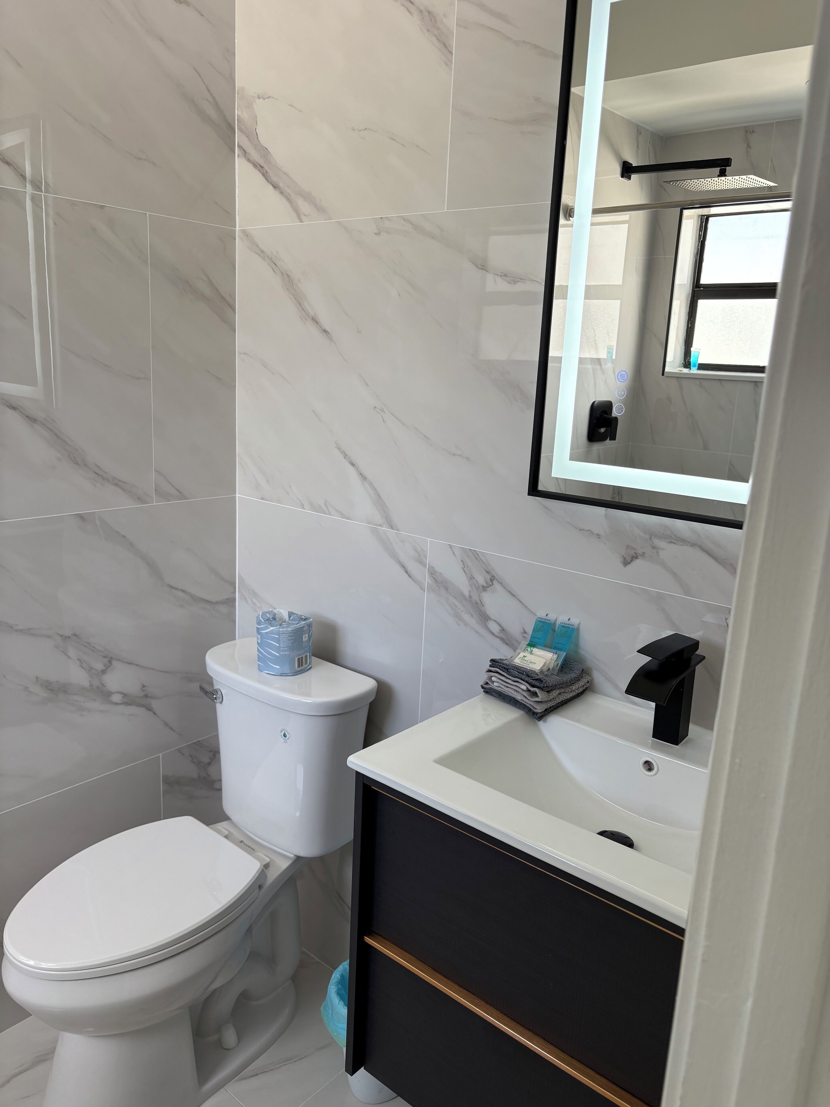 A bathroom with a toilet, sink, and mirror.