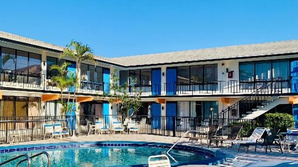 A hotel with a pool area, multiple balconies, and outdoor seating. - Oceans 735 (Deerfield Beach)
