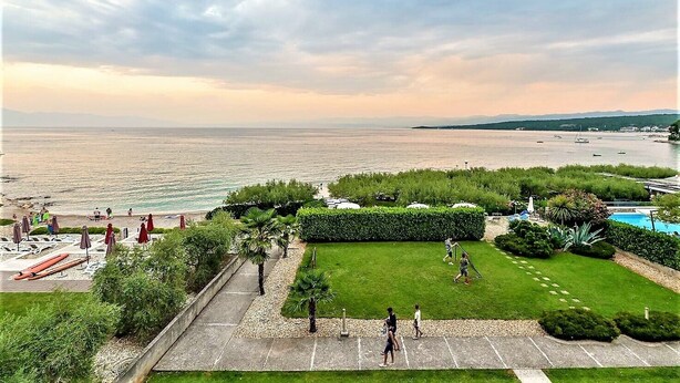 Une vue sur la côte, avec une zone herbeuse, des sentiers pédestres et une plage en arrière-plan.